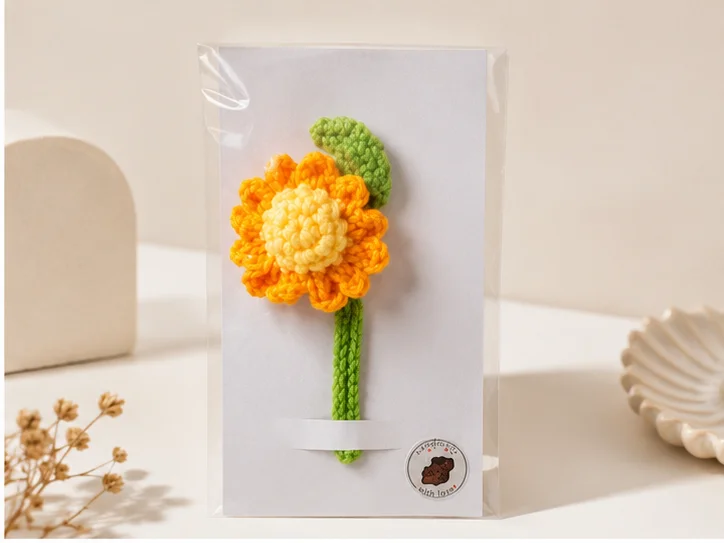 Handmade crochet marigold bookmark with colorful floral design and green leaf